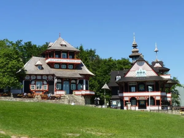 Na obrázku vidíme dřevěné domky na Pustevnách od jednoho slavného československého architekta. Se kterým lázeňským městem je nejvíce spjat?